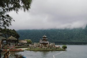 A serene view of the Ulun Danu Beratan Temple surrounded by misty mountains and Lake Beratan.